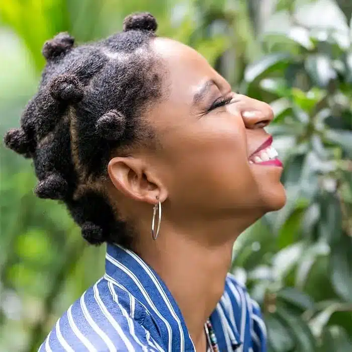 a black lady with smiling face with Bantu Knots hair style