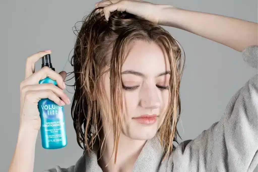 a lady applying voulmizing mousse on hair