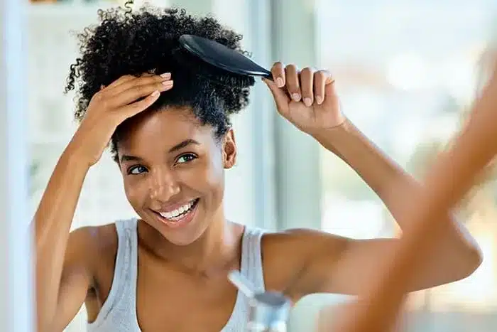 a lady brushing her hair while looking in the mirror