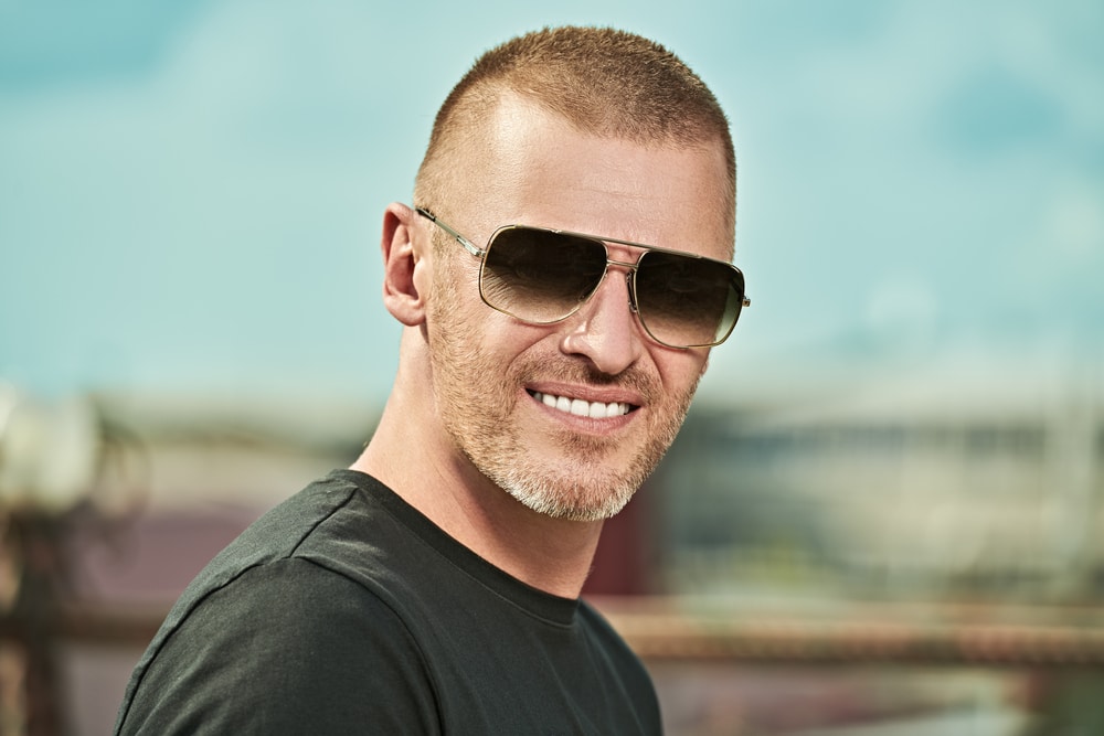 Portrait of a handsome brutal mature man with short hair and bristles wearing trendy sunglasses outdoor