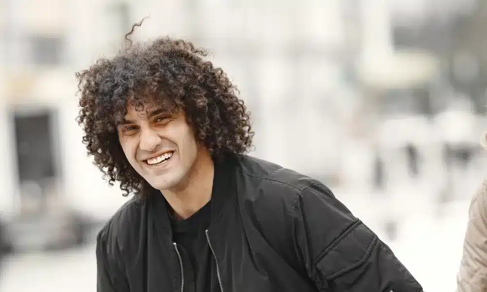 a man smiling having long curly hair