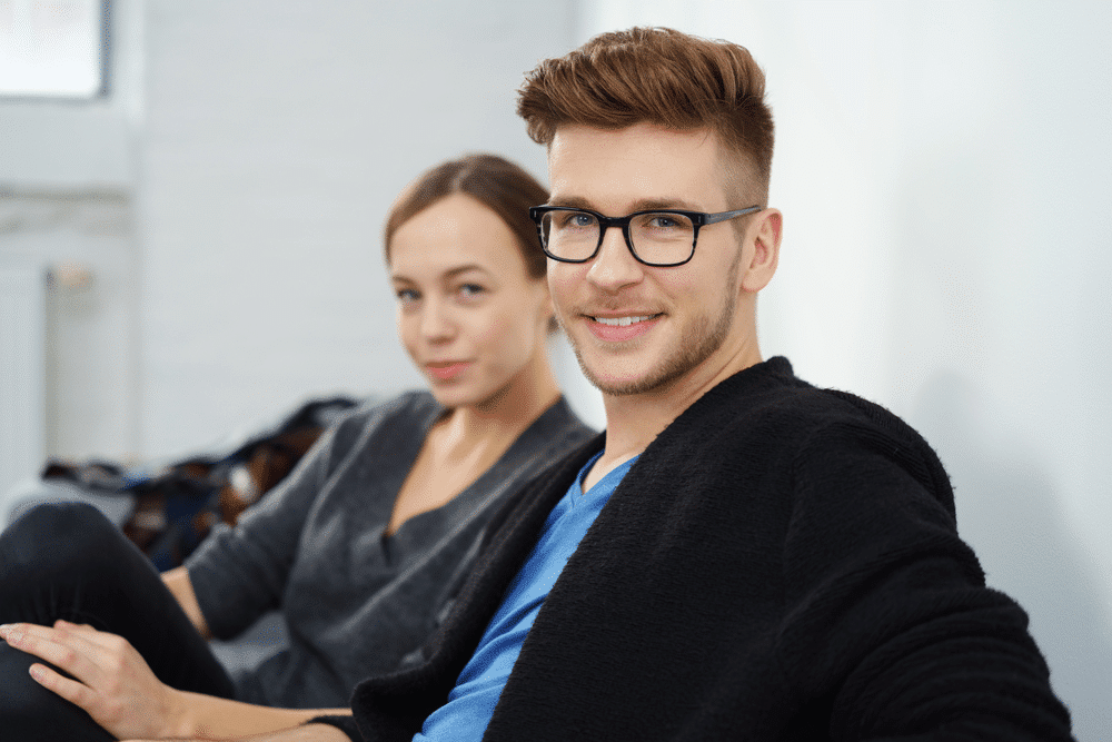 a man with quiff haircut with a woman in the background