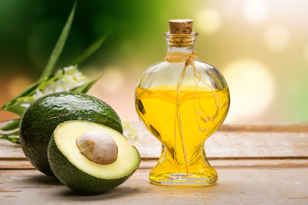 avocado oil bottle with cut and whole avocado